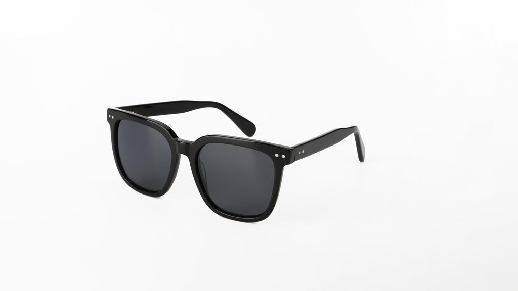 Black square sunglasses with dark lenses and small silver rivets, shown at an angle on a clean white background.